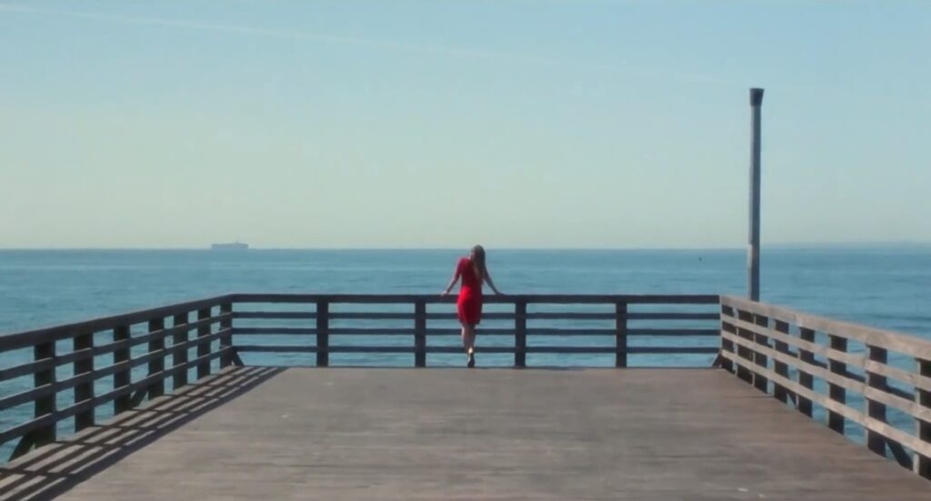 海辺の柵にマリオン(ジェニファー・コネリー)らしき女性がもたれているシーンの画像。